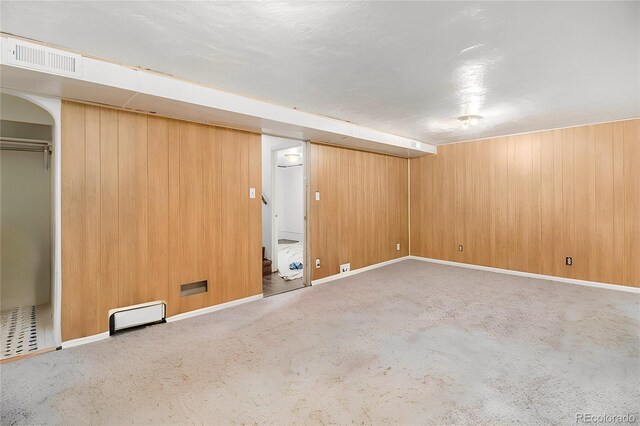 finished below grade area with baseboards, baseboard heating, visible vents, and carpet flooring