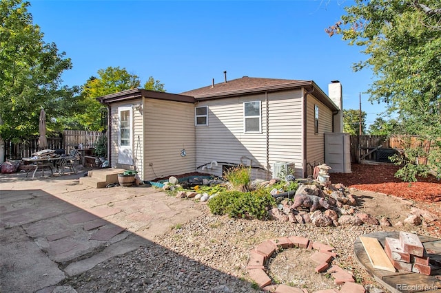 back of house with a patio area, a fenced backyard, and a chimney