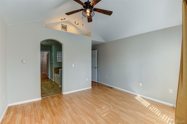 spare room with visible vents, arched walkways, a ceiling fan, wood finished floors, and vaulted ceiling