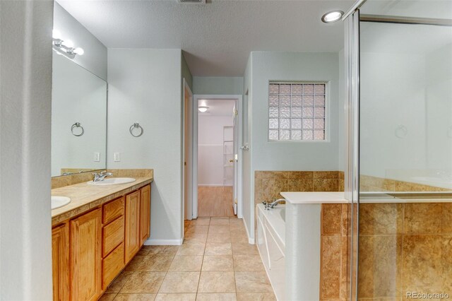 bathroom featuring a garden tub, tile patterned flooring, a textured ceiling, a shower stall, and a sink