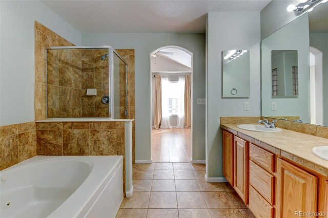 bathroom with double vanity, a stall shower, a sink, tile patterned flooring, and a bath