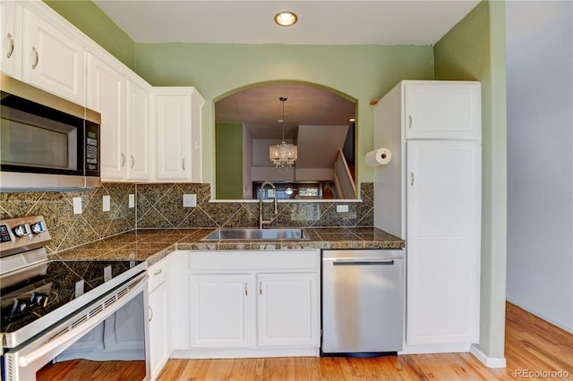 kitchen featuring tile counters, white cabinets, decorative backsplash, stainless steel appliances, and a sink