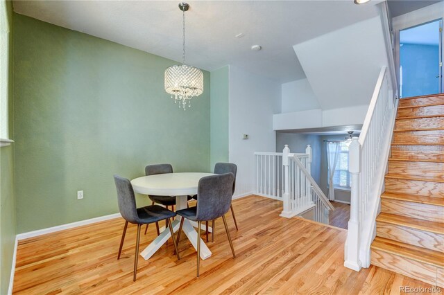 dining room with a chandelier, stairway, wood finished floors, and baseboards