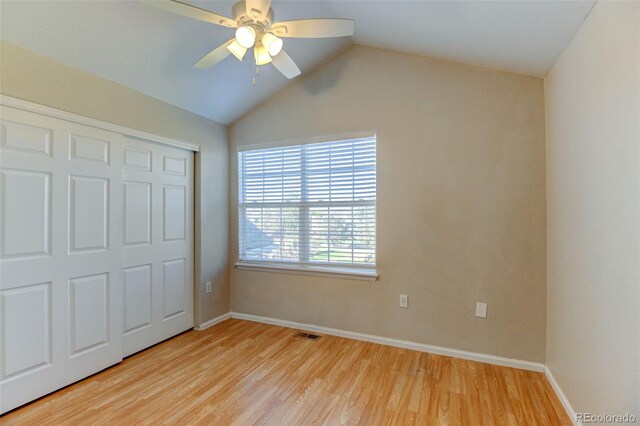 unfurnished bedroom with light wood-type flooring, a closet, lofted ceiling, and baseboards