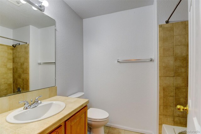 full bathroom with a textured wall, vanity, toilet, and tile patterned floors