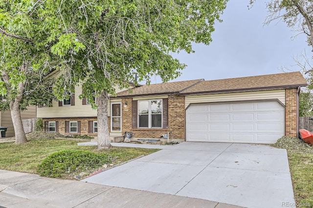 tri-level home featuring brick siding, an attached garage, concrete driveway, and a front yard