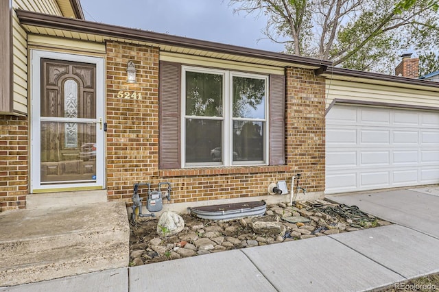 entrance to property with brick siding and an attached garage