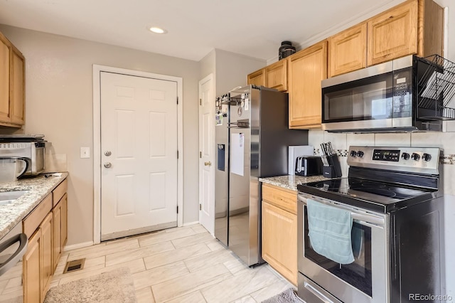 kitchen featuring light brown cabinetry, visible vents, stainless steel appliances, and light stone counters