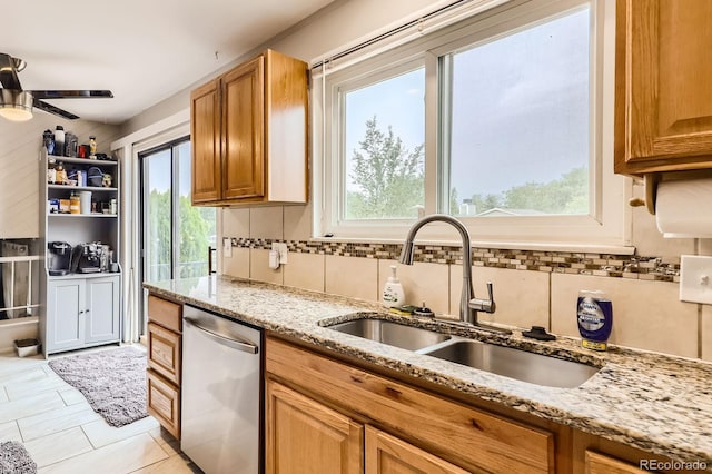 kitchen featuring a ceiling fan, a sink, backsplash, light stone countertops, and dishwasher