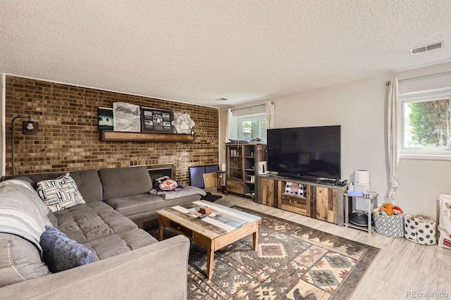 living room with wood finished floors, visible vents, a wealth of natural light, and a textured ceiling