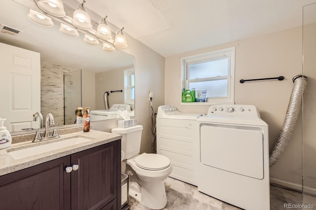 bathroom with visible vents, washer and clothes dryer, toilet, vanity, and a shower