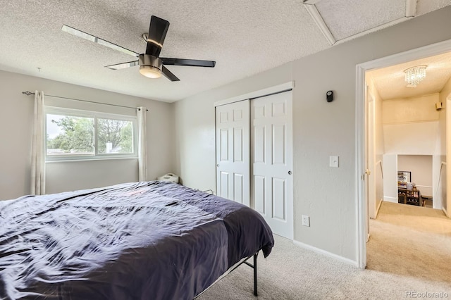 carpeted bedroom with a ceiling fan, baseboards, attic access, a closet, and a textured ceiling