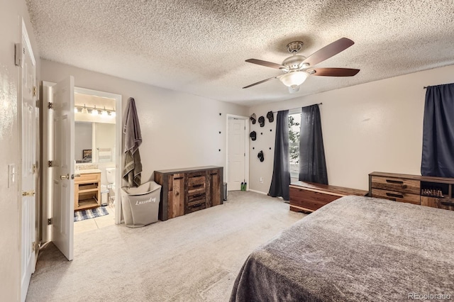 bedroom featuring light carpet, a textured ceiling, ensuite bathroom, and a ceiling fan