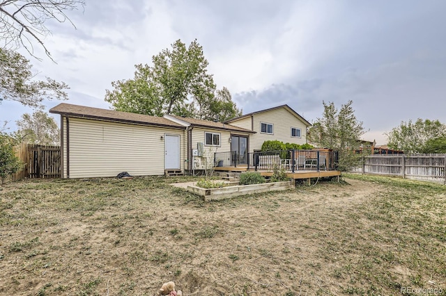 rear view of house with a yard, a deck, a fenced backyard, and a vegetable garden