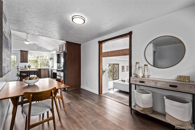 dining area with lofted ceiling, a ceiling fan, baseboards, and dark wood-style flooring