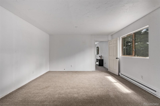 empty room featuring a baseboard heating unit and carpet