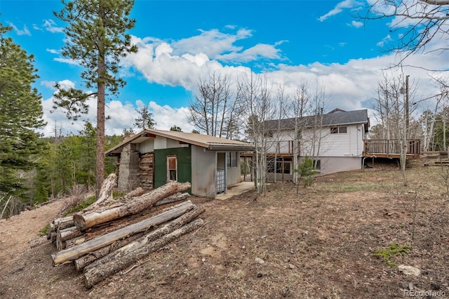 rear view of property featuring a wooden deck and stucco siding