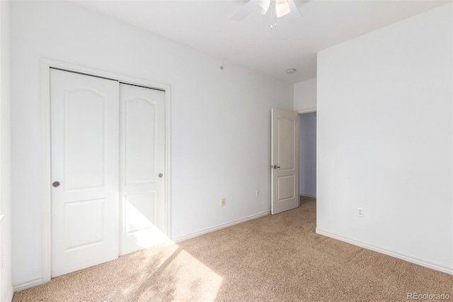 unfurnished bedroom featuring light carpet, ceiling fan, and a closet