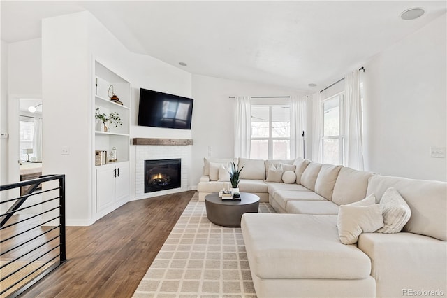 living room with hardwood / wood-style floors, built in features, and vaulted ceiling