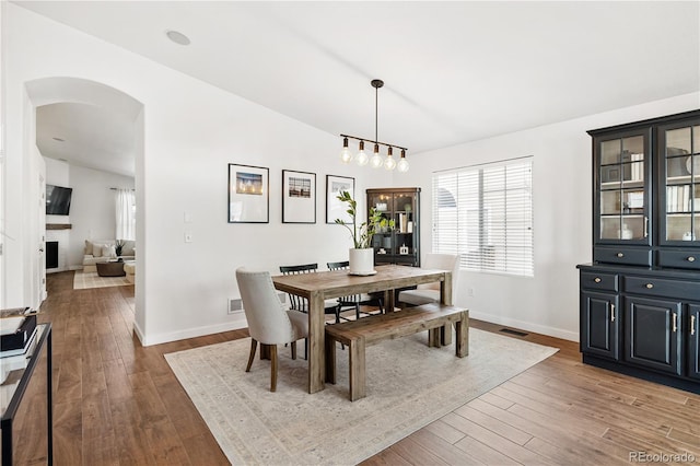 dining room with dark wood-type flooring and vaulted ceiling