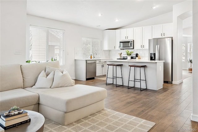 living room with hardwood / wood-style floors, lofted ceiling, and sink