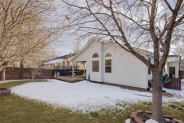 snow covered rear of property with a deck