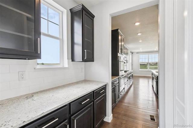 27196 E Alder Dr, Aurora, CO 80016 - kitchen with dark wood-style floors, decorative backsplash, glass insert cabinets, recessed lighting, and light stone countertops