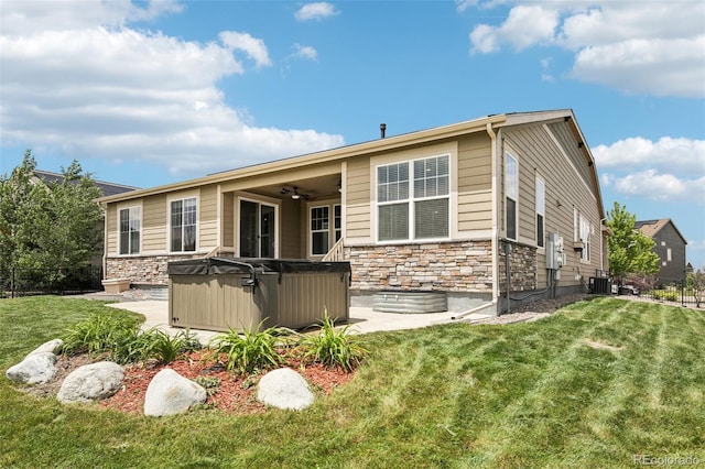 27196 E Alder Dr, Aurora, CO 80016 - rear view of house with a hot tub, stone siding, a ceiling fan, and a lawn