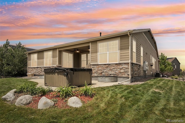 27196 E Alder Dr, Aurora, CO 80016 - rear view of house with a hot tub, stone siding, a yard, a ceiling fan, and a patio