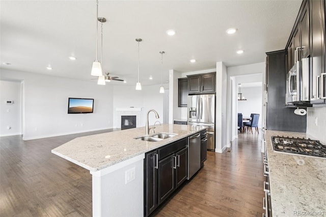 27196 E Alder Dr, Aurora, CO 80016 - kitchen featuring appliances with stainless steel finishes, dark wood-style flooring, open floor plan, a glass covered fireplace, and ceiling fan