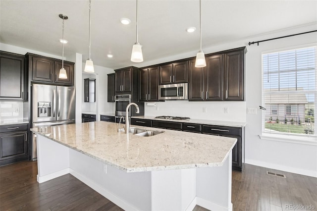27196 E Alder Dr, Aurora, CO 80016 - kitchen featuring stainless steel appliances, dark wood-type flooring, a center island with sink, light stone countertops, and recessed lighting