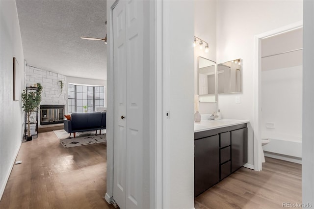 2620 S Federal Blvd Unit K, Denver, CO 80219 - full bath with wood finished floors, vanity, a textured ceiling, and a fireplace