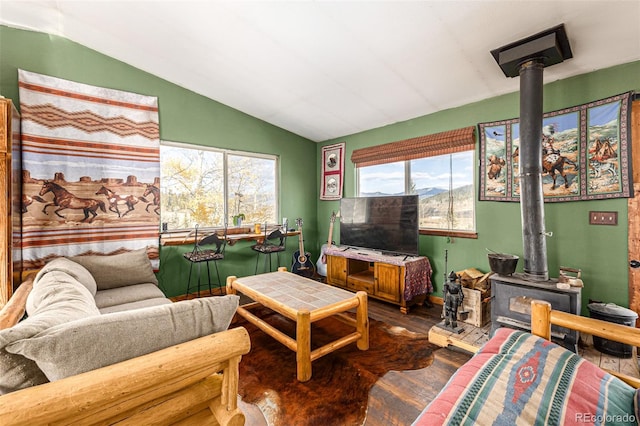 living room featuring lofted ceiling, hardwood / wood-style floors, and a wood stove