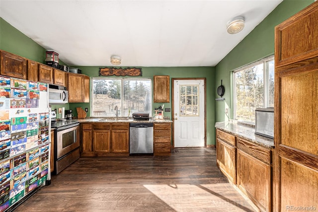 kitchen with vaulted ceiling, sink, light stone counters, stainless steel appliances, and dark hardwood / wood-style floors