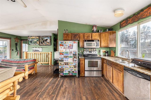 kitchen with lofted ceiling, sink, stone counters, stainless steel appliances, and dark hardwood / wood-style floors