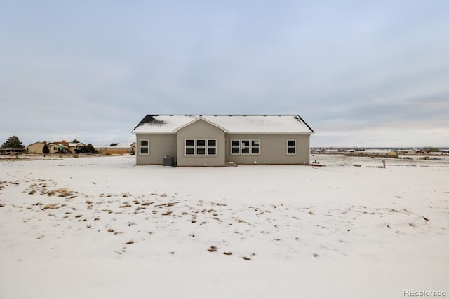 snow covered rear of property featuring central AC