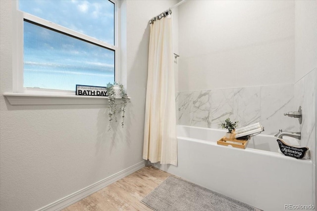 bathroom with hardwood / wood-style flooring and a tub to relax in