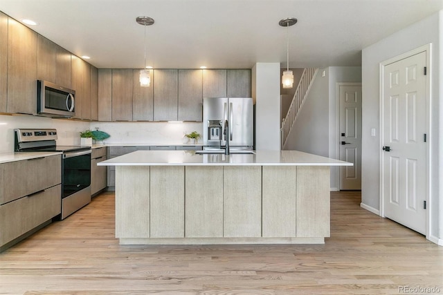 10470 W Cooper Pl, Littleton, CO 80127 - kitchen featuring stainless steel appliances, light countertops, a center island with sink, light wood-style floors, and recessed lighting