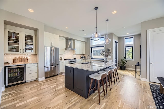6849 E Lowry Blvd, Denver, CO 80230 - kitchen with high end fridge, beverage cooler, wall chimney range hood, a sink, and light wood-style floors
