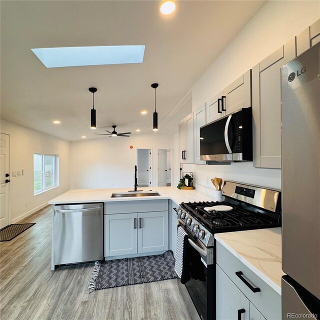 7200 E State Highway 14 Unit 27, Fort Collins, CO 80524 - kitchen featuring appliances with stainless steel finishes, a sink, a peninsula, light wood finished floors, and a skylight