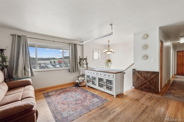 living area with a chandelier, visible vents, baseboards, and wood finished floors