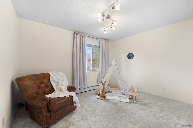 sitting room with a textured ceiling, light colored carpet, and a baseboard heating unit