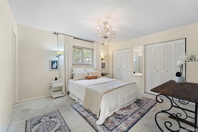 carpeted bedroom featuring multiple closets, a textured ceiling, and an inviting chandelier