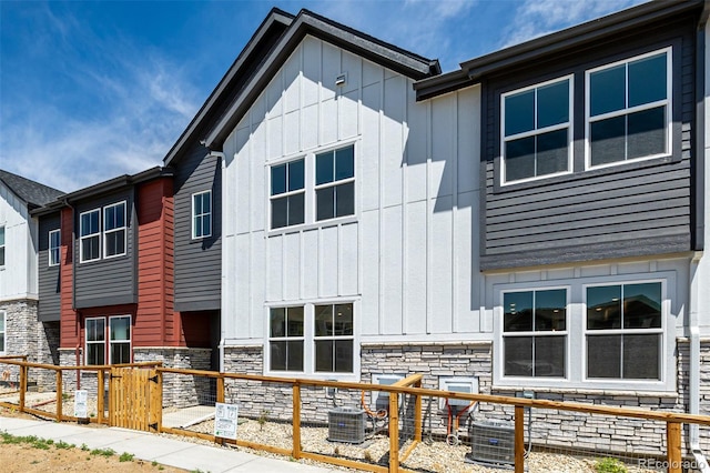 2887 E 103rd Dr, Thornton, CO 80229 - rear view of property with board and batten siding, stone siding, and cooling unit