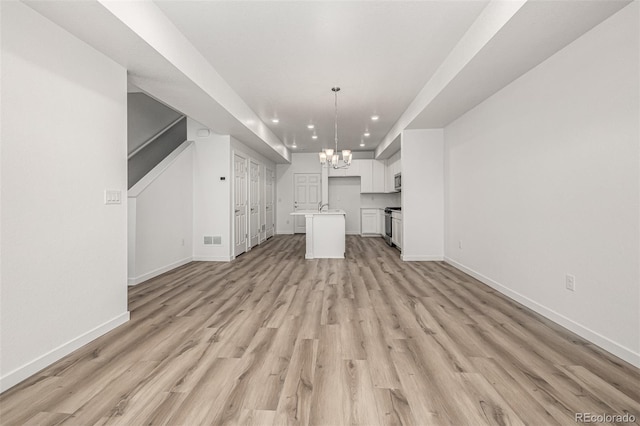 2887 E 103rd Dr, Thornton, CO 80229 - unfurnished living room with a chandelier, recessed lighting, baseboards, light wood-style floors, and a sink