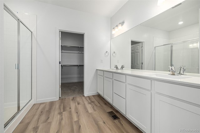 2887 E 103rd Dr, Thornton, CO 80229 - bathroom featuring wood finished floors, a stall shower, double vanity, and a spacious closet