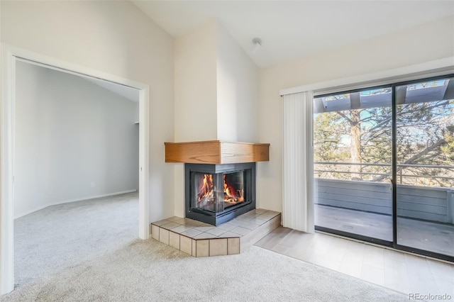 unfurnished living room featuring a tile fireplace, light colored carpet, and vaulted ceiling