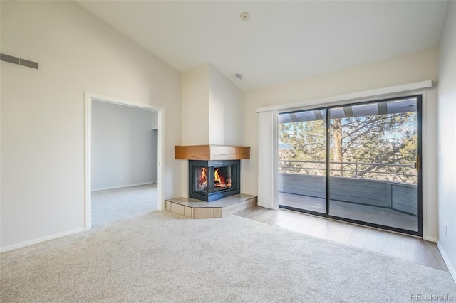 unfurnished living room with high vaulted ceiling, light carpet, and a tile fireplace