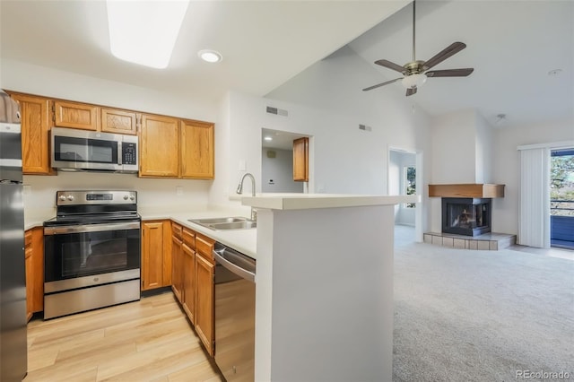 kitchen with kitchen peninsula, appliances with stainless steel finishes, a tile fireplace, and sink