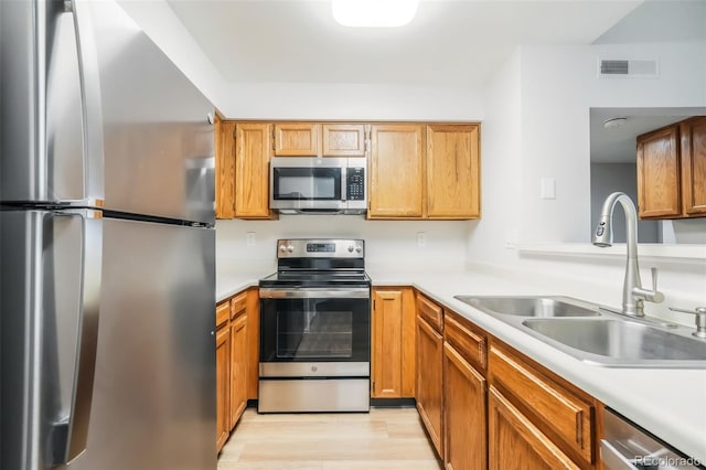 kitchen with sink, stainless steel appliances, and light hardwood / wood-style floors